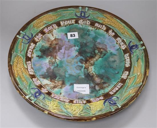 A Victorian majolica bread dish, late 19th century, with a motto, wheatsheaf and sickle border, unmarked, diameter 38.5cm